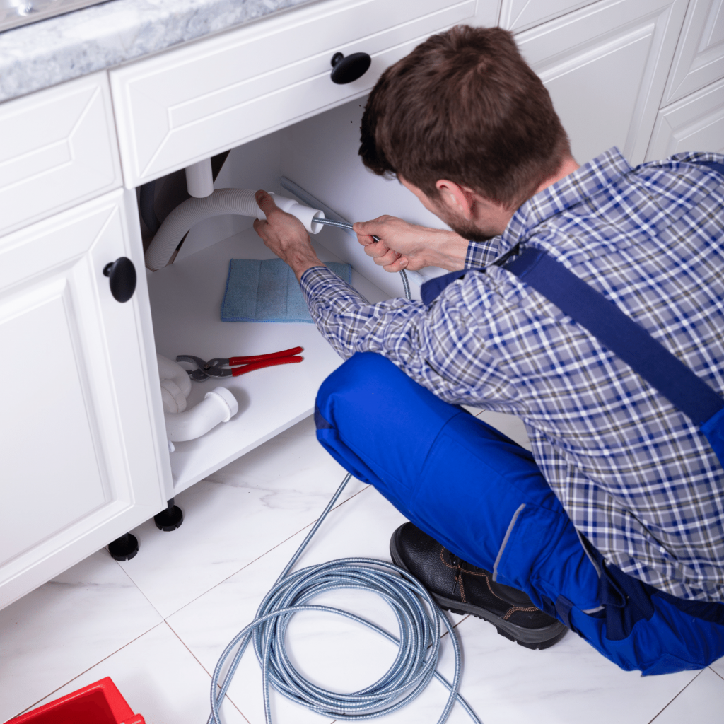 Ein Techniker führt eine Rohrreinigung unter einem Waschbecken durch, Rohrreinigung Hannover